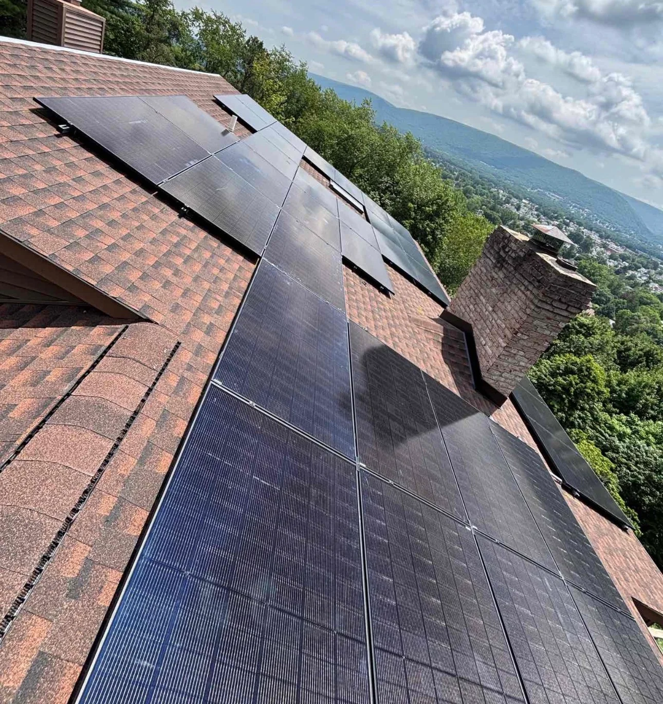 Solar panels installed on brick residential home with mountain valley view in background