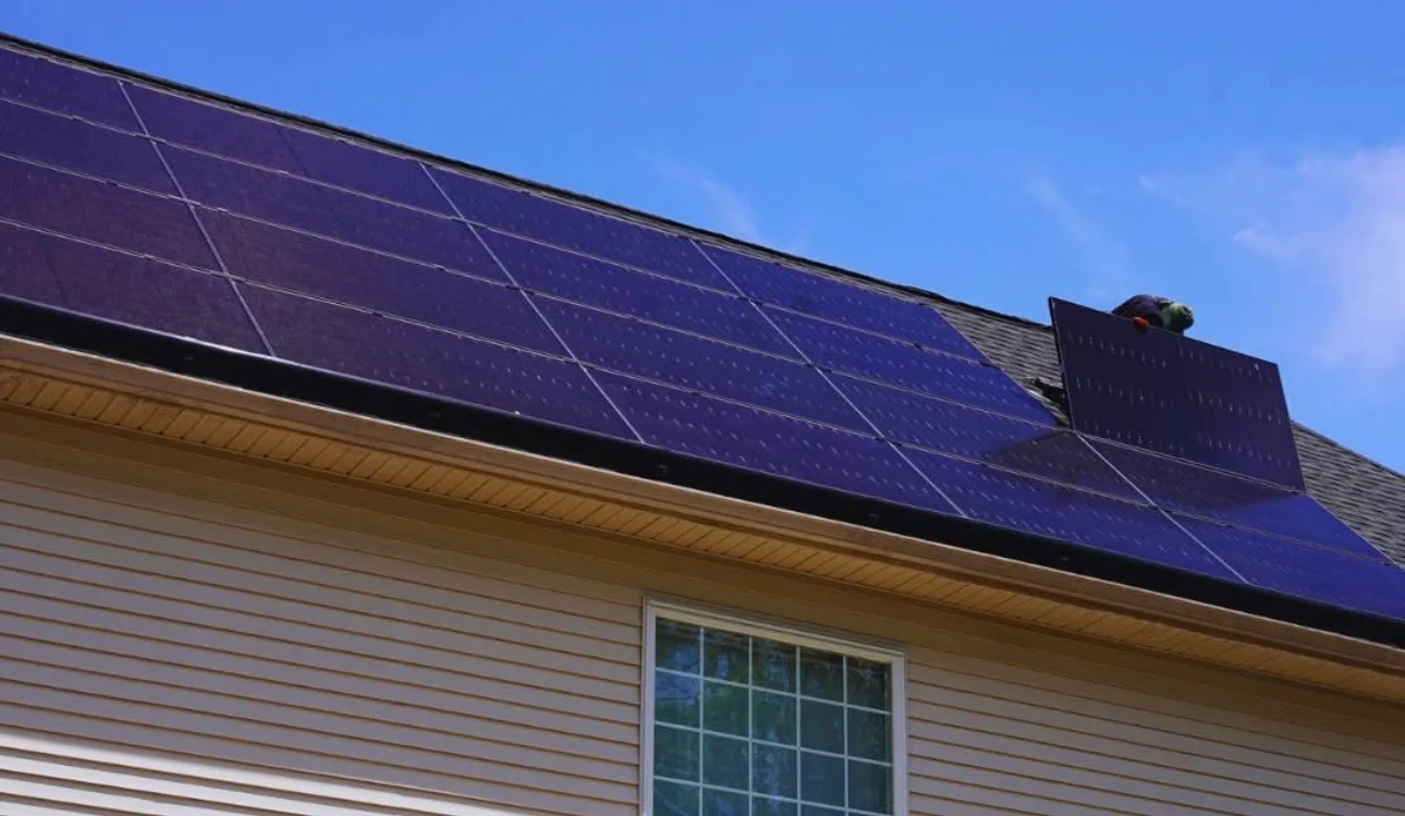 Blue solar panels installed on residential roof with clear sky background